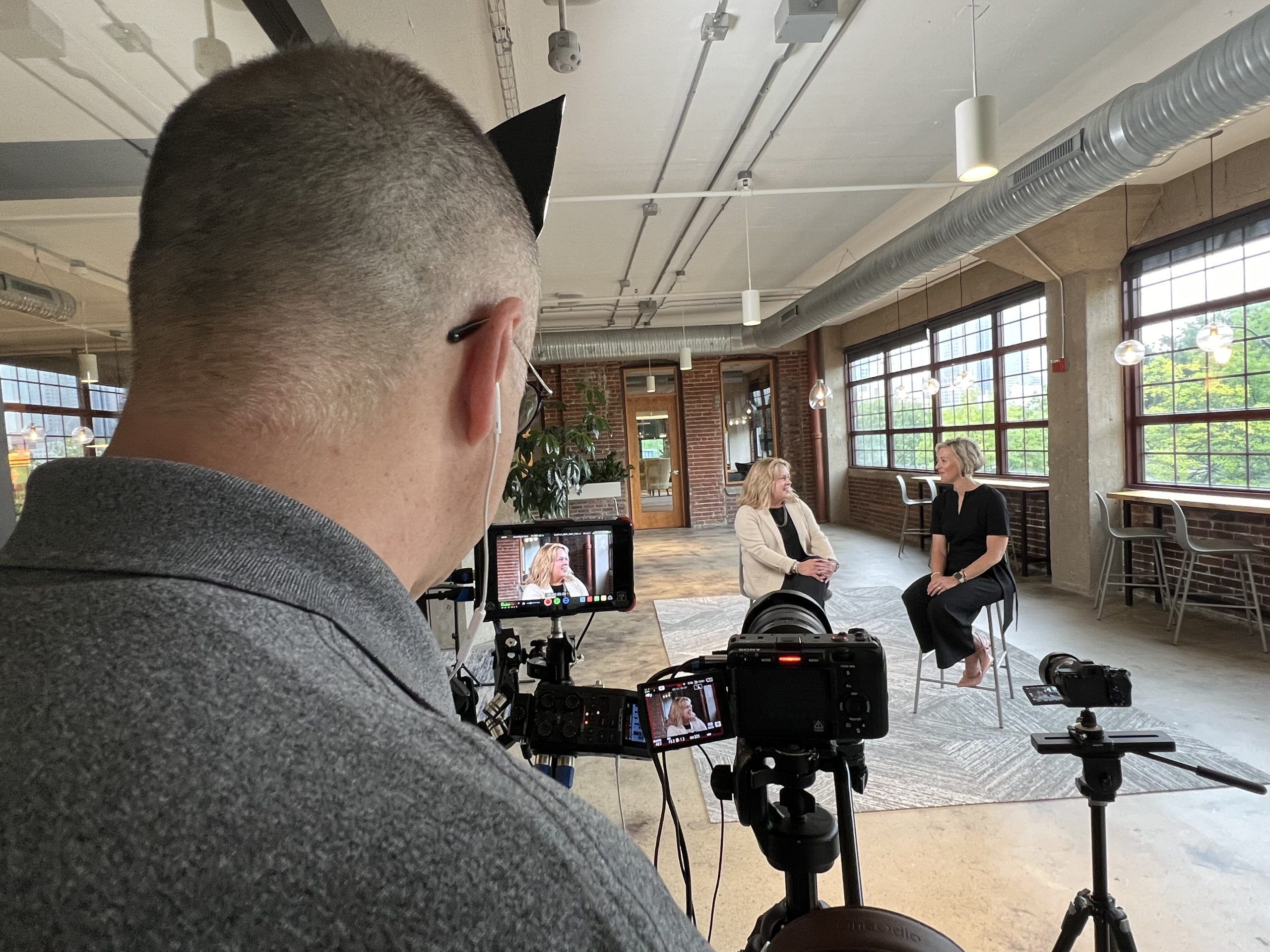Behind-the-scenes photo of two women, business partners, talking during a promo video shoot. Shows authentic interaction.