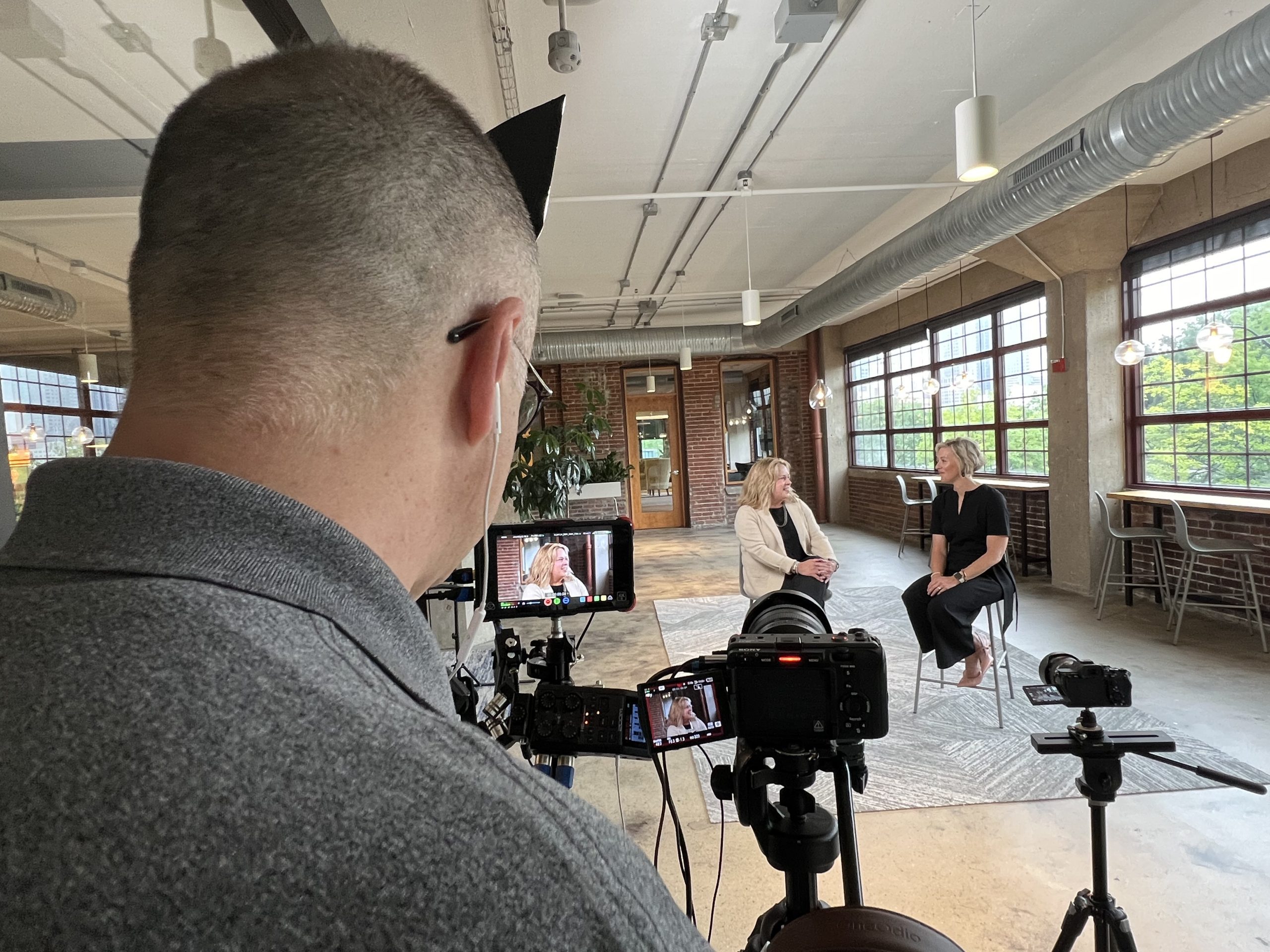 Behind-the-scenes photo of two women, business partners, talking during a promo video shoot. Shows authentic interaction.